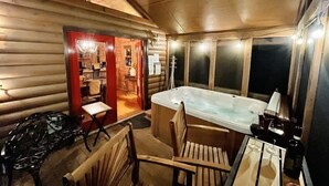 A log cabin interior with a hot tub, wooden furniture, and a dining area. - BEAR CROSSING - HOT TUB, GAME ROOM, SECLUDED (Helen)