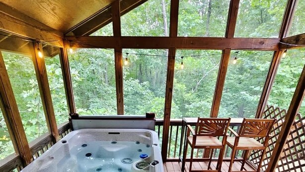 A hot tub on a wooden deck with a view of a forest. - BEAR CROSSING - HOT TUB, GAME ROOM, SECLUDED (Helen)