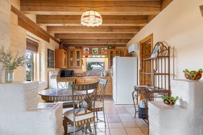 A rustic kitchen with wooden beams, a round dining table, and a refrigerator. - Adobe Vista - Cozy and Inviting Spectacular View (Alpine)