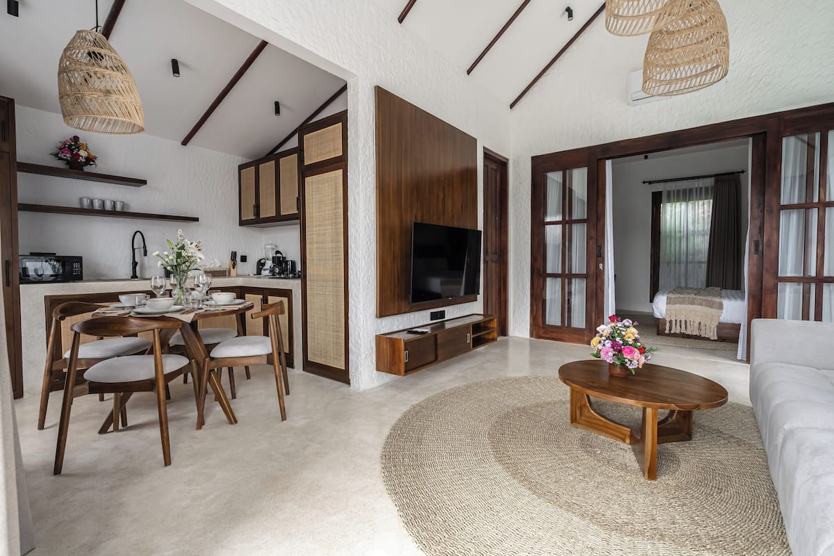 Ein modernes Wohnzimmer mit Fernseher, Sofa und Essbereich.