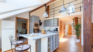 A spacious kitchen with a large island, wooden flooring, and a loft area with exposed beams. - Spacious 2-level apart National Theatre (Prague)