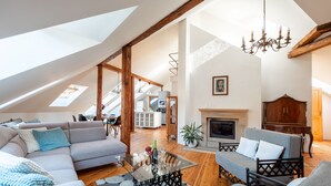 A spacious living room with a high ceiling, a fireplace, and a dining area visible in the background. - Spacious 2-level apart National Theatre (Prague)