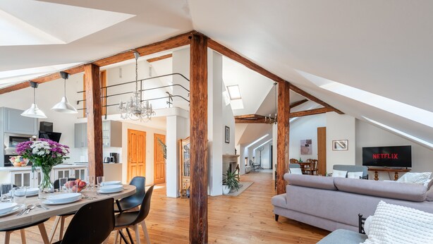 A spacious loft with a dining area, a living room with a sofa, and a TV displaying 'NETFLIX'. - Spacious 2-level apart National Theatre (Prague)