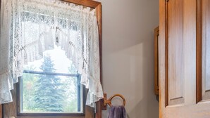 Une porte en bois avec une fenêtre, un rideau en dentelle, une serviette accrochée à un crochet et un meuble en bois avec des tiroirs.