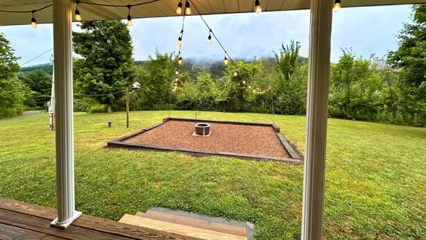 Un espace extérieur aménagé en terrasse, avec une plateforme en bois, un foyer et des guirlandes lumineuses.