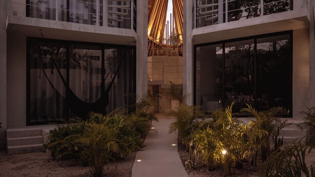 A modern building with a central atrium, large windows, and a unique roof design. - Seremonia Selva (Tulum)
