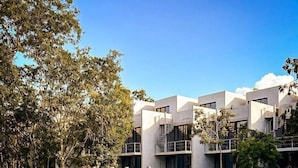 A modern hotel with a pool area, including a hot tub and lounge chairs. - Seremonia Selva (Tulum)