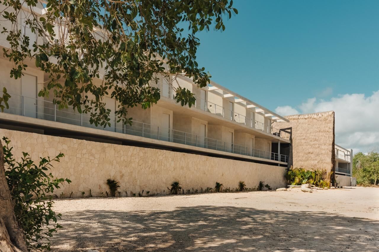 Un edificio moderno con una fachada larga y plana, varios balcones y un amplio patio abierto.