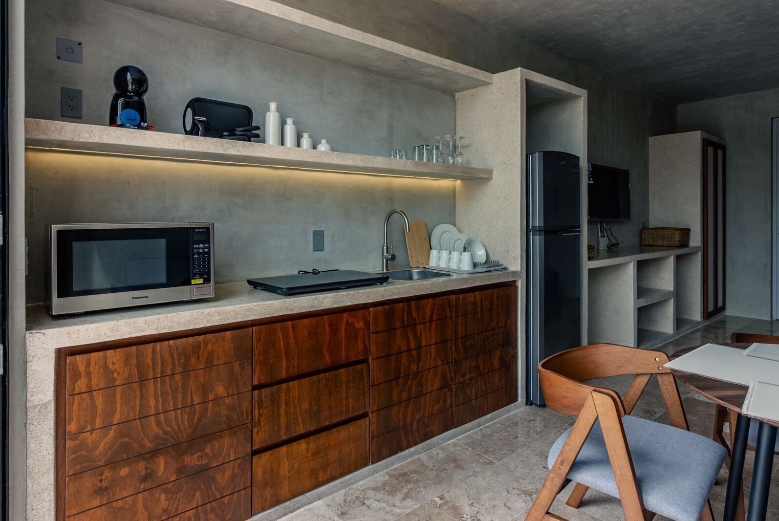 A modern kitchen with a built-in microwave, a coffee machine, and a sink.