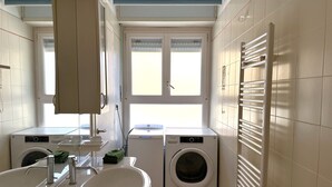 Ein Waschraum mit zwei Waschmaschinen mit Frontlader, einem Waschbecken und einem Fenster.