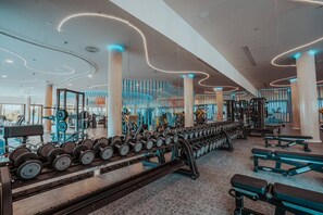A modern gym with weightlifting equipment, benches, and a variety of exercise machines.