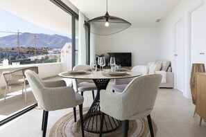 A modern dining area with a round table, chairs, and a hanging light fixture.