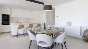 A modern kitchen with white cabinetry, a central island, and a dining area with a round table set for four.