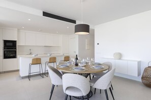A modern kitchen with white cabinetry, a central island, and a dining area with a round table set for four.