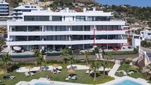 A modern hotel with a pool area, multiple floors, and a view of the surrounding landscape.