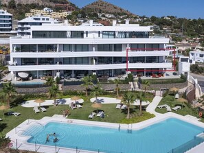 A modern hotel with a pool area, multiple floors, and a view of the surrounding landscape.