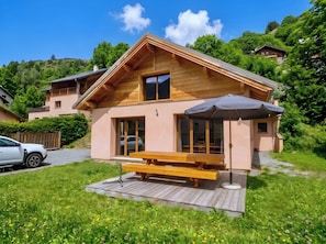 A wooden cabin with a deck, a bench, and a table.