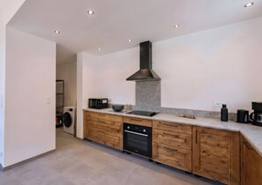 A modern kitchen with built-in appliances, a central island, and a large range hood.