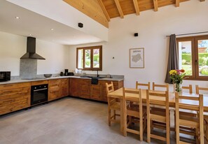 A modern kitchen with wooden cabinets, a built-in oven, and a dining area with a wooden table and chairs.