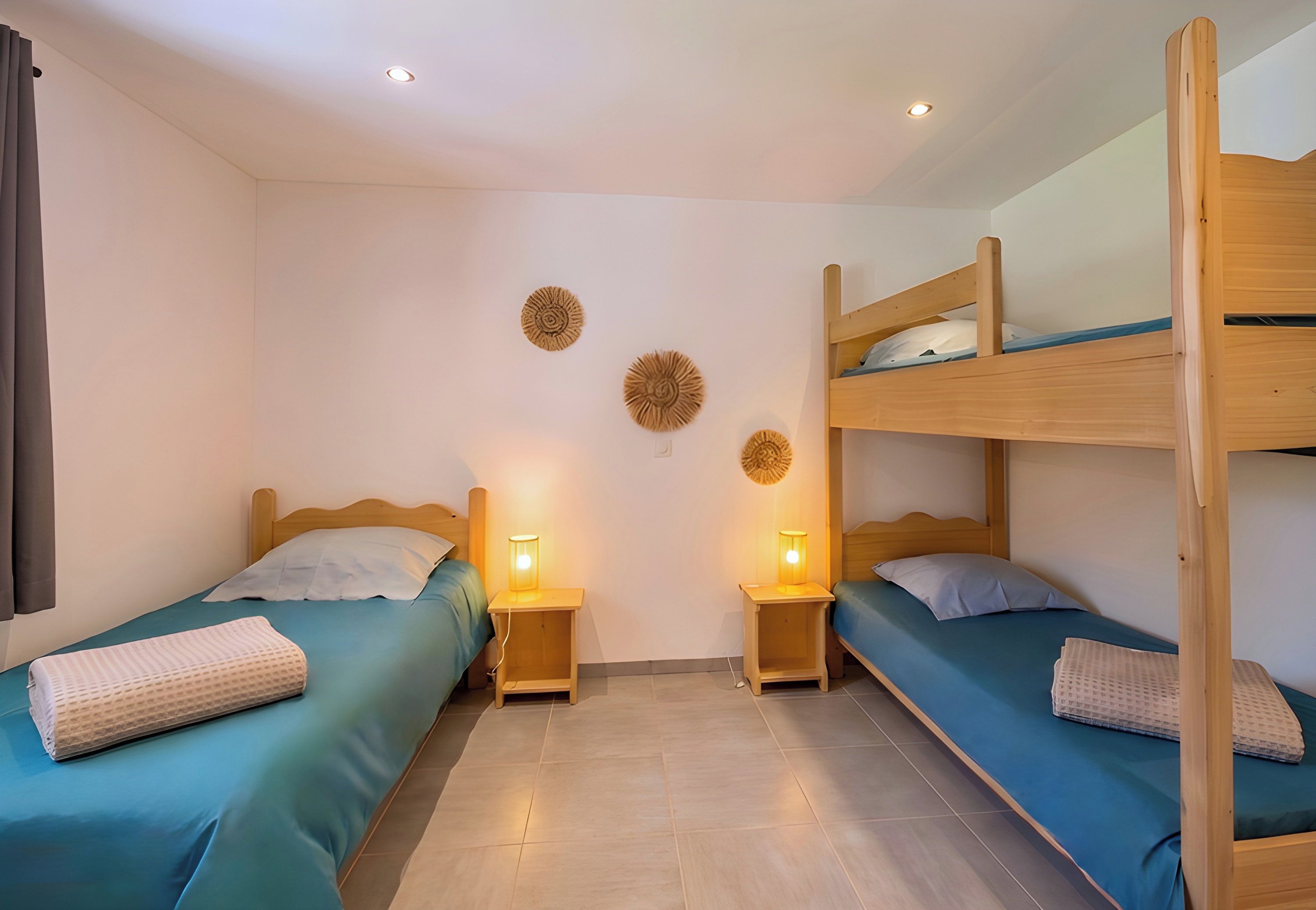 Een kamer met twee eenpersoonsbedden, een stapelbed, houten hoofdeinden, nachtlampjes en decoratie aan de muur.
