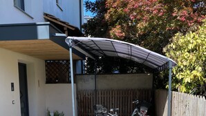 A covered outdoor area with a bicycle, a wooden fence, and a garden with various plants. - Modern apartment with large balcony. Near city center. (Meran)