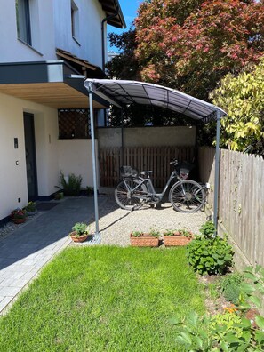 A covered outdoor area with a bicycle, a wooden fence, and a garden with various plants. - Modern apartment with large balcony. Near city center. (Meran)