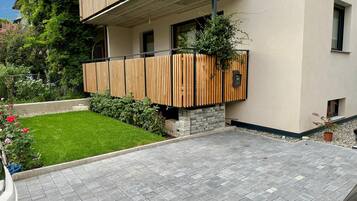 Ein modernes, zweistöckiges Gebäude mit flachem Dach, einem kleinen Garten und einer gepflasterten Auffahrt.