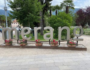 A large metal sign spelling 'merane' with potted flowers at its base.