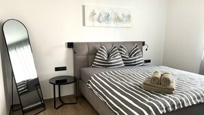 A modern bedroom with a bed, a bedside table, a mirror, and a wall-mounted artwork. - Modern apartment with large balcony. Near city center. (Meran)