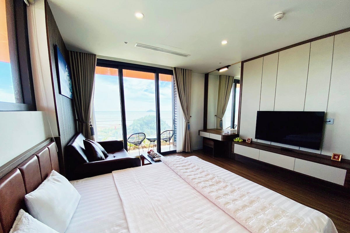 Une chambre d’hôtel avec un grand lit, une télévision, un bureau et une vue sur l’océan.