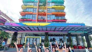 Un edificio de varios pisos con balcones, una entrada cubierta y una zona de piscina.