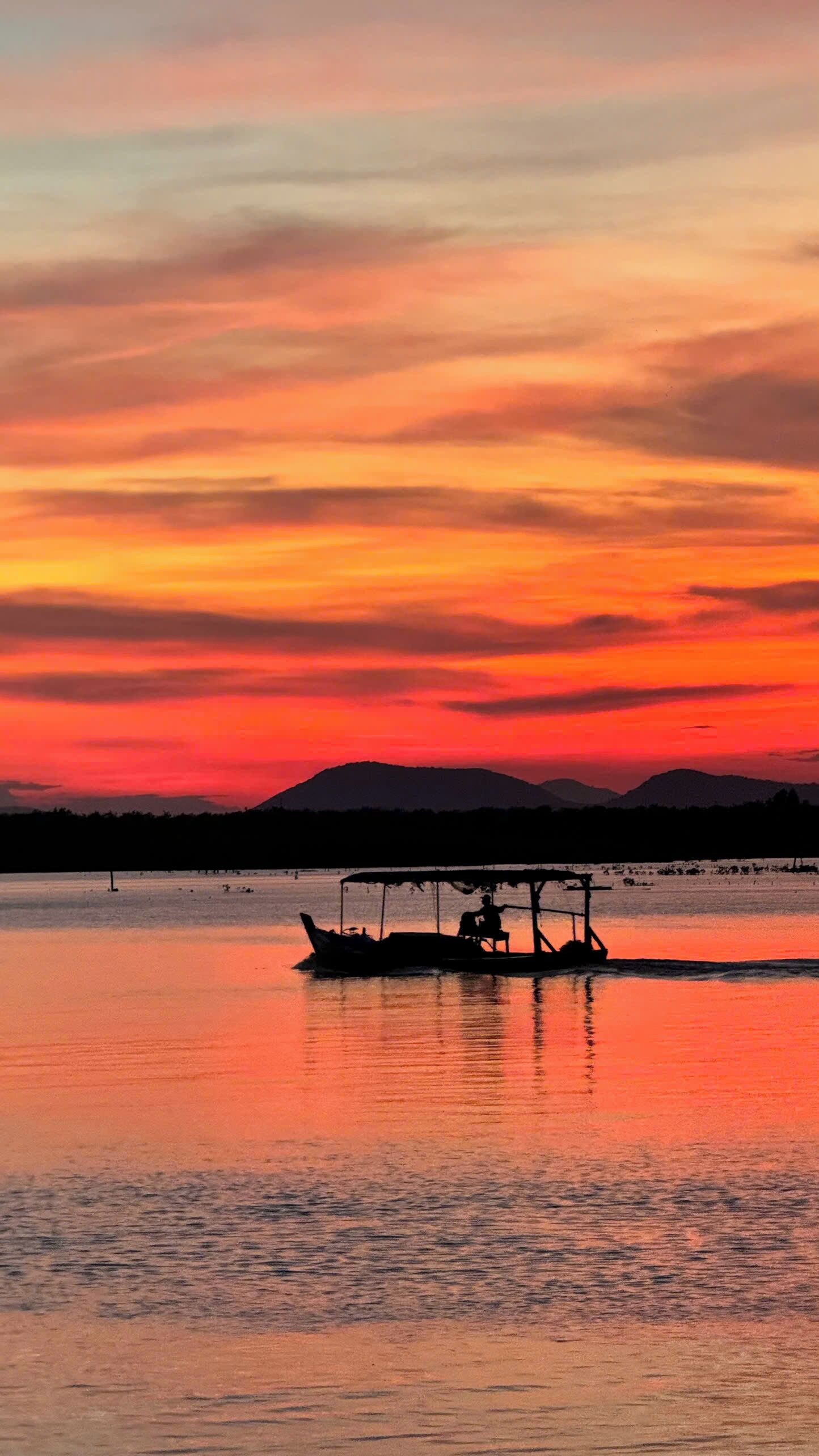 Un bote en aguas tranquilas durante el atardecer, con una montaña al fondo.