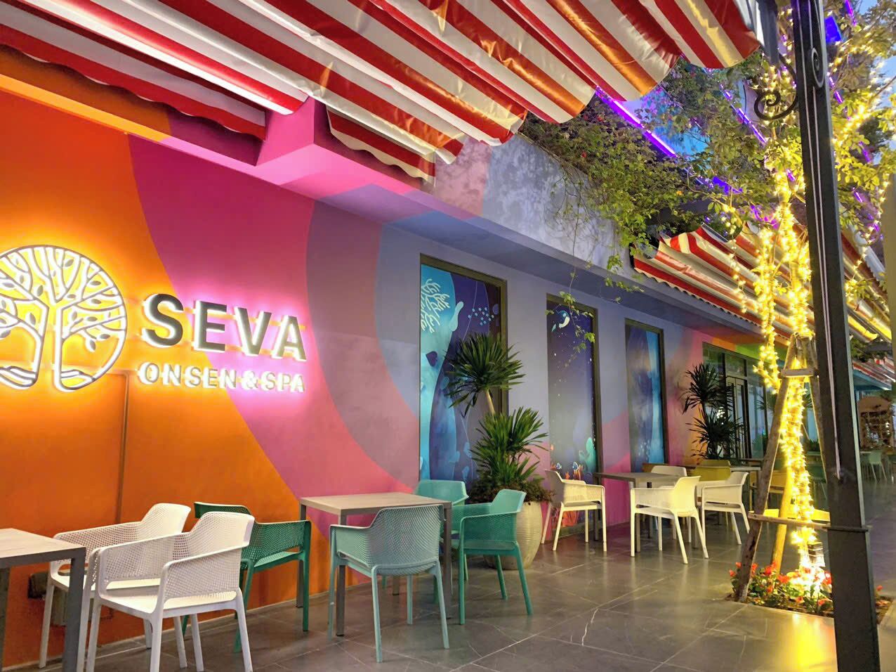 Een terras met zitgedeelte, een kleurrijke muur en de naam "SEVA ONSEN&SPA".