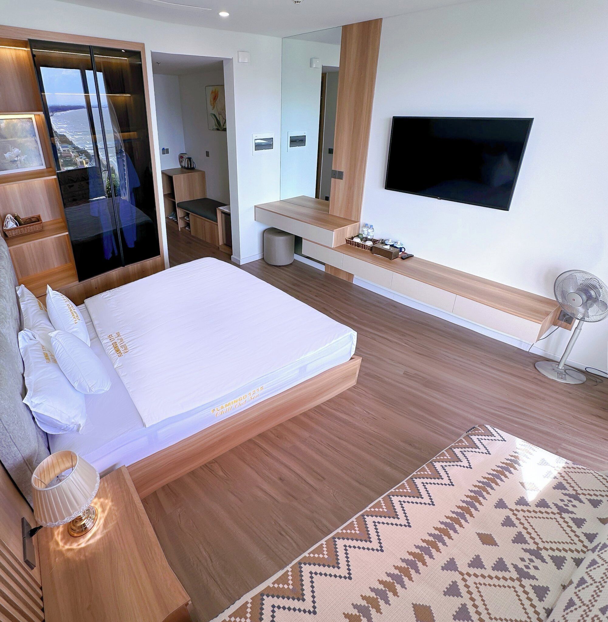 Un dormitorio moderno con una cama grande, un televisor, un escritorio y vista al mar.