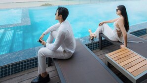 A couple sitting by a pool with a view of the sea and a distant island. - Flamingo Hai Tien  (Hoang Tien)
