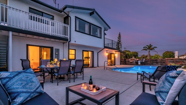 Une terrasse extérieure moderne, dotée d’une piscine, d’un espace salon et d’un coin repas.