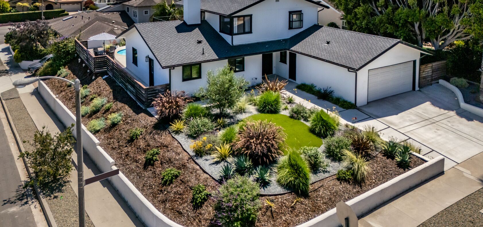 A modern two-story house with a well-maintained garden featuring a variety of plants and a small pond.