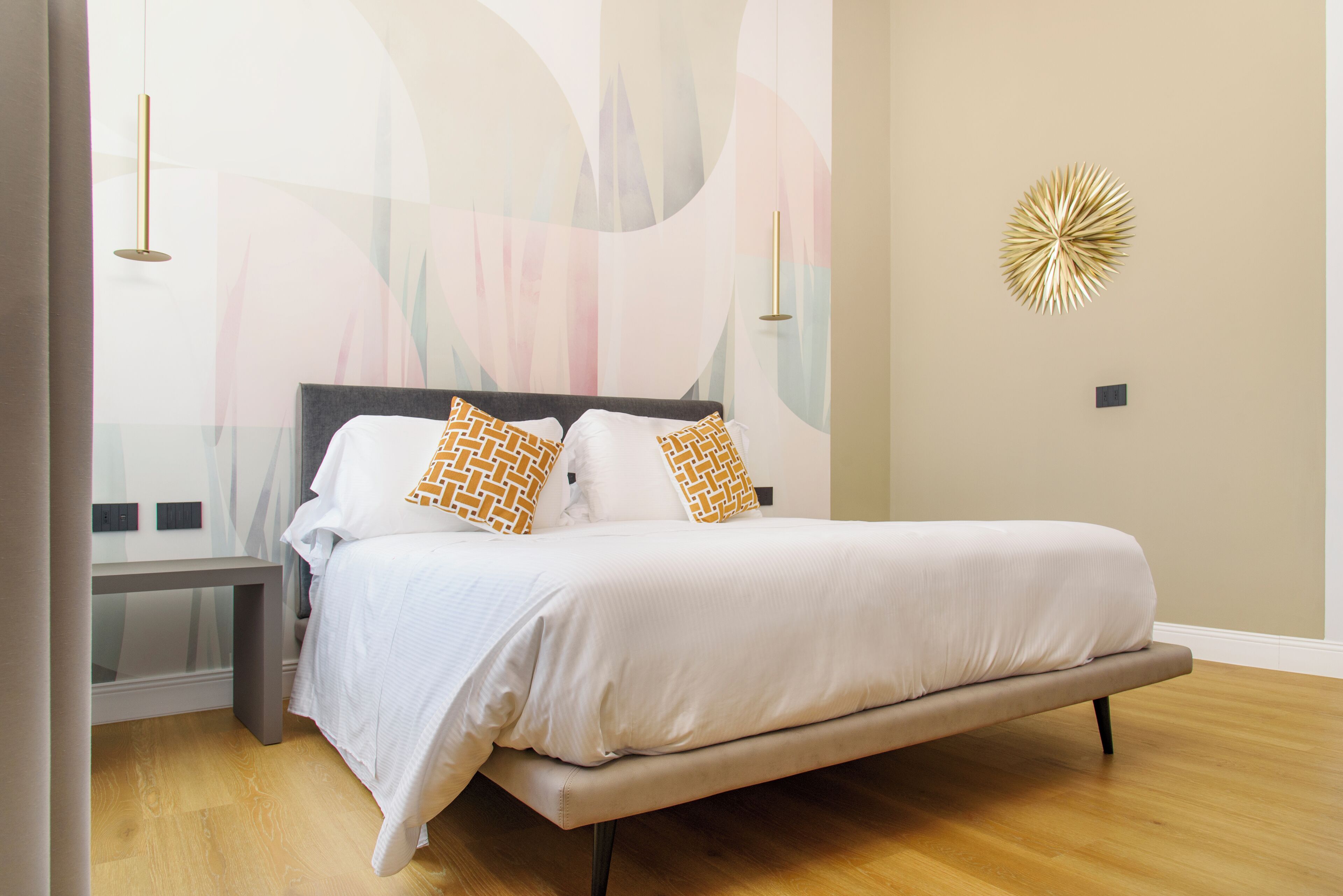 A modern bedroom with a bed, bedside tables, and abstract wall art.