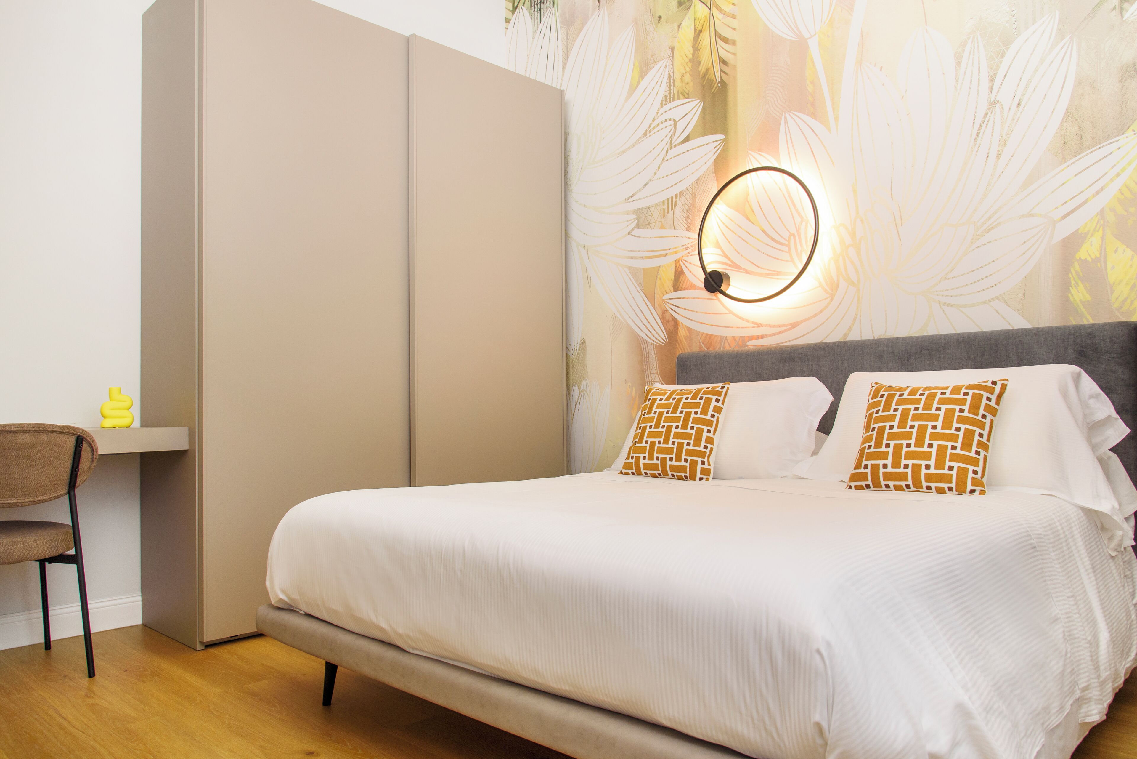 A bedroom with a bed, a desk, and a wardrobe.