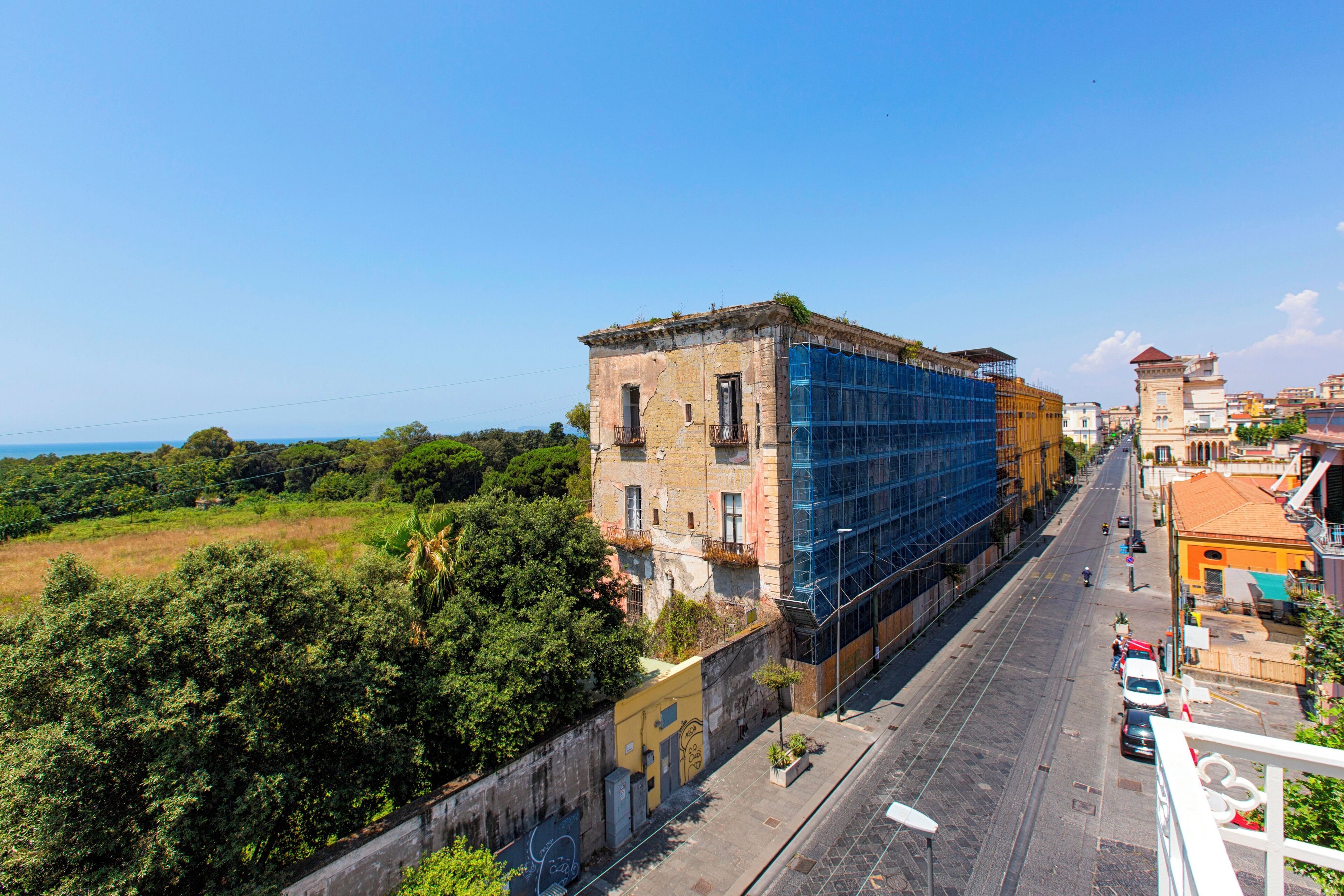A street view with a building under construction, a clear sky, and a distant view of a tower.