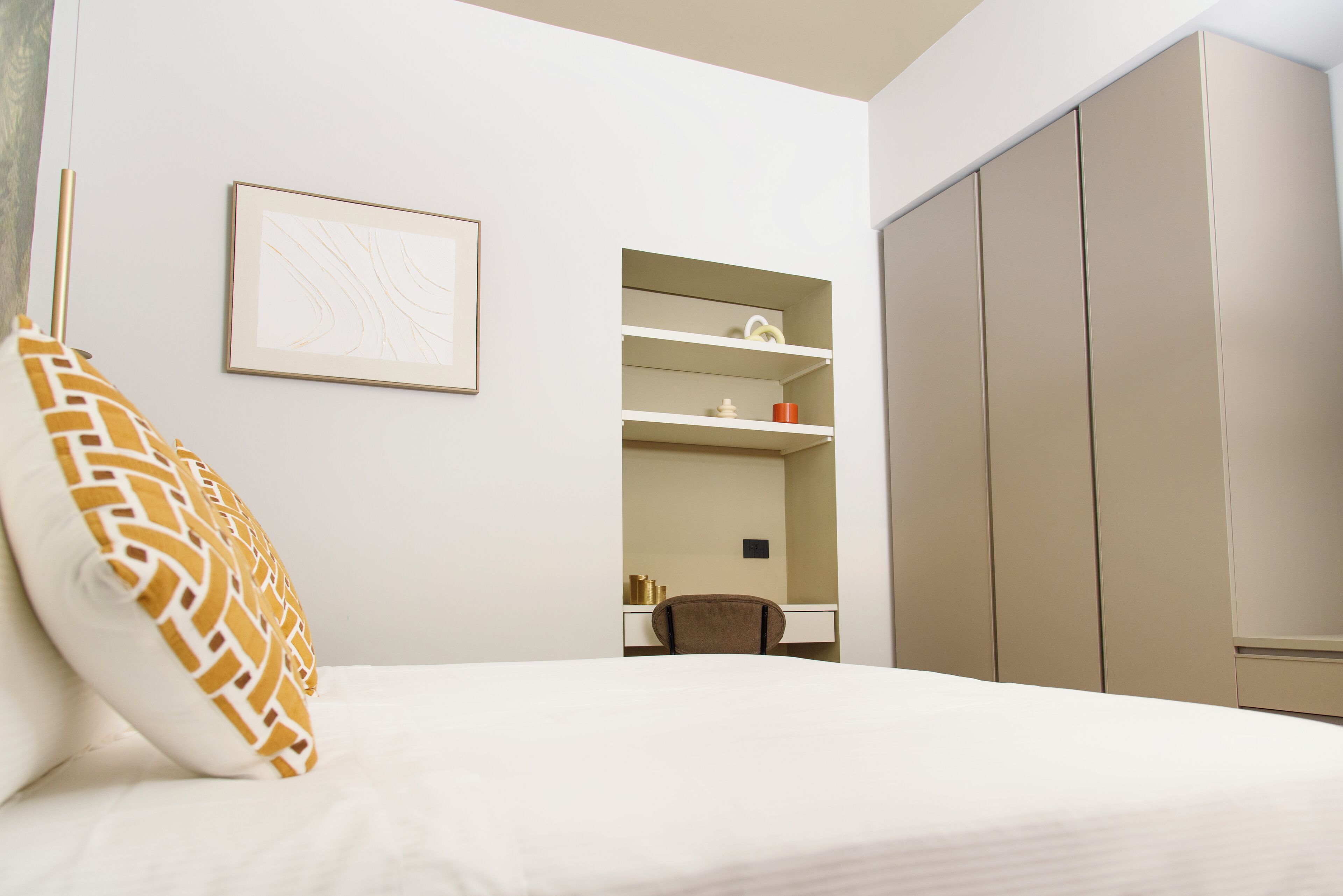 A hotel room with a bed, a desk, a chair, and a wardrobe.