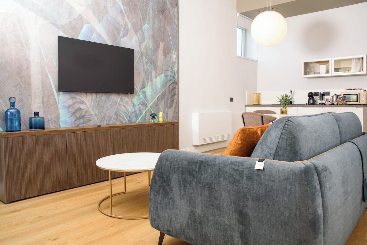 A modern living room with a grey sofa, a round coffee table, and a wooden cabinet.
