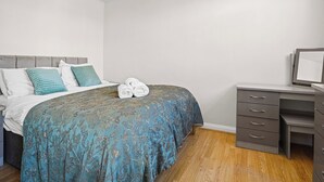Ein Schlafzimmer mit Bett, Schreibtisch und Kleiderschrank.