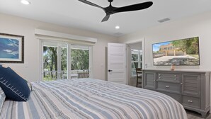 A bedroom with a bed, a ceiling fan, a dresser, and a television on the wall. - Stunning, brand new - July 2024 - 3-bedroom villa with River view (Homosassa)
