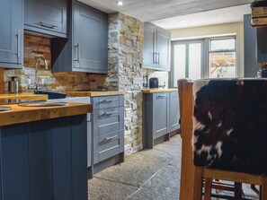 A modern kitchen with grey cabinets, a stone accent wall, and a wooden countertop. - 2 bedroom accommodation in Hook Norton, near Chipping Norton (Hook Norton, near Chipping Norton)