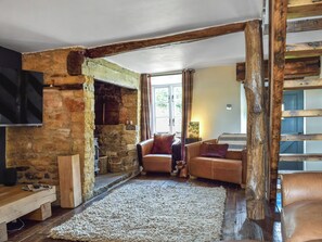 A rustic interior with exposed stone walls, a wooden bench, a leather sofa, and a large rug. - 2 bedroom accommodation in Hook Norton, near Chipping Norton (Hook Norton, near Chipping Norton)