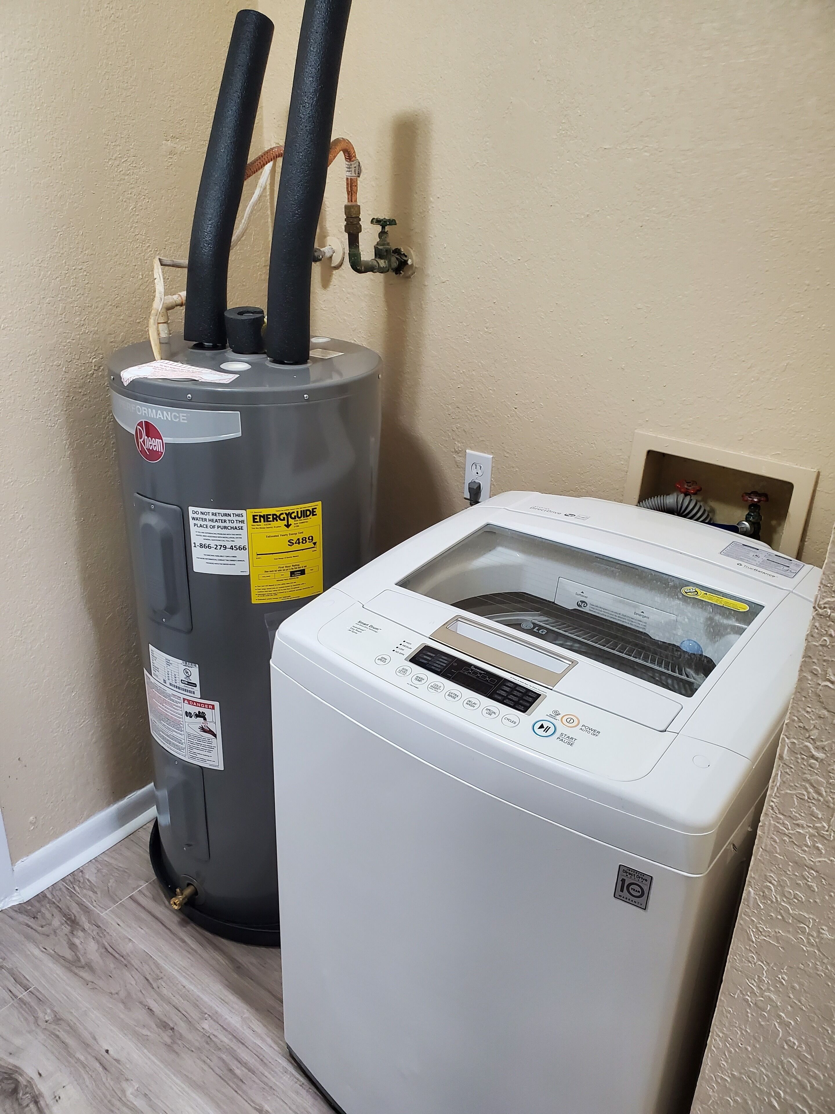 Een boiler en een airconditioner in een kamer met beige muren en houten vloeren.