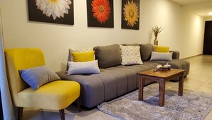 Una sala de estar moderna con un sofá, un sillón y una mesa de centro. Hay tres grandes cuadros florales en la pared.
