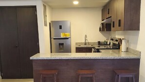 Una cocina con una isla central, armarios de madera oscura, un refrigerador de acero inoxidable y un lavamanos.