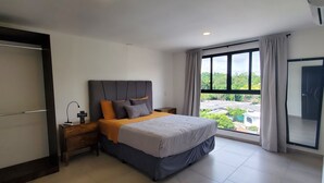 Un dormitorio con cama, mesitas de noche, armario y una ventana grande con vistas.